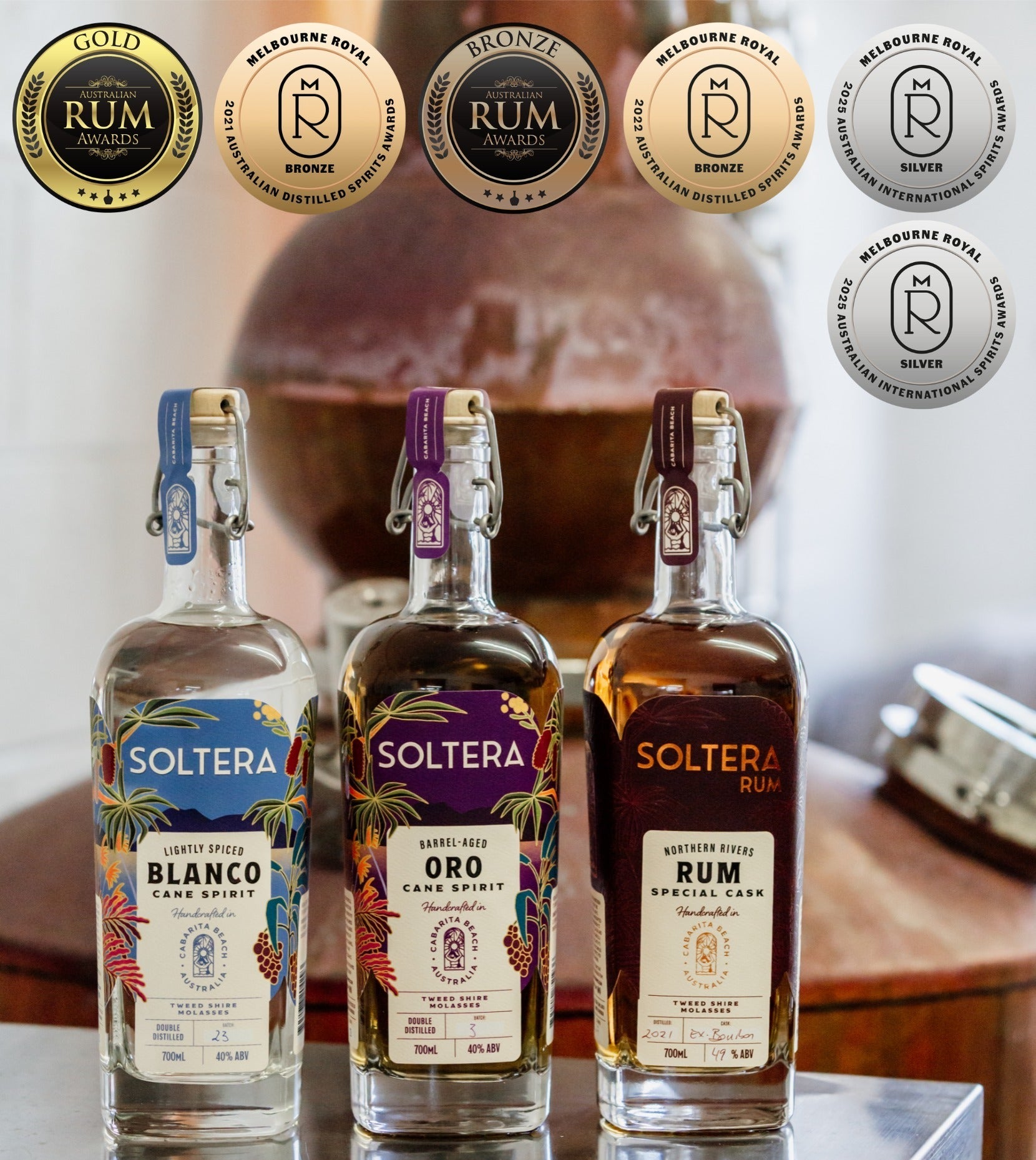 Three Soltera rum bottles with decorative labels on a reflective surface, featuring brand logos in the background.