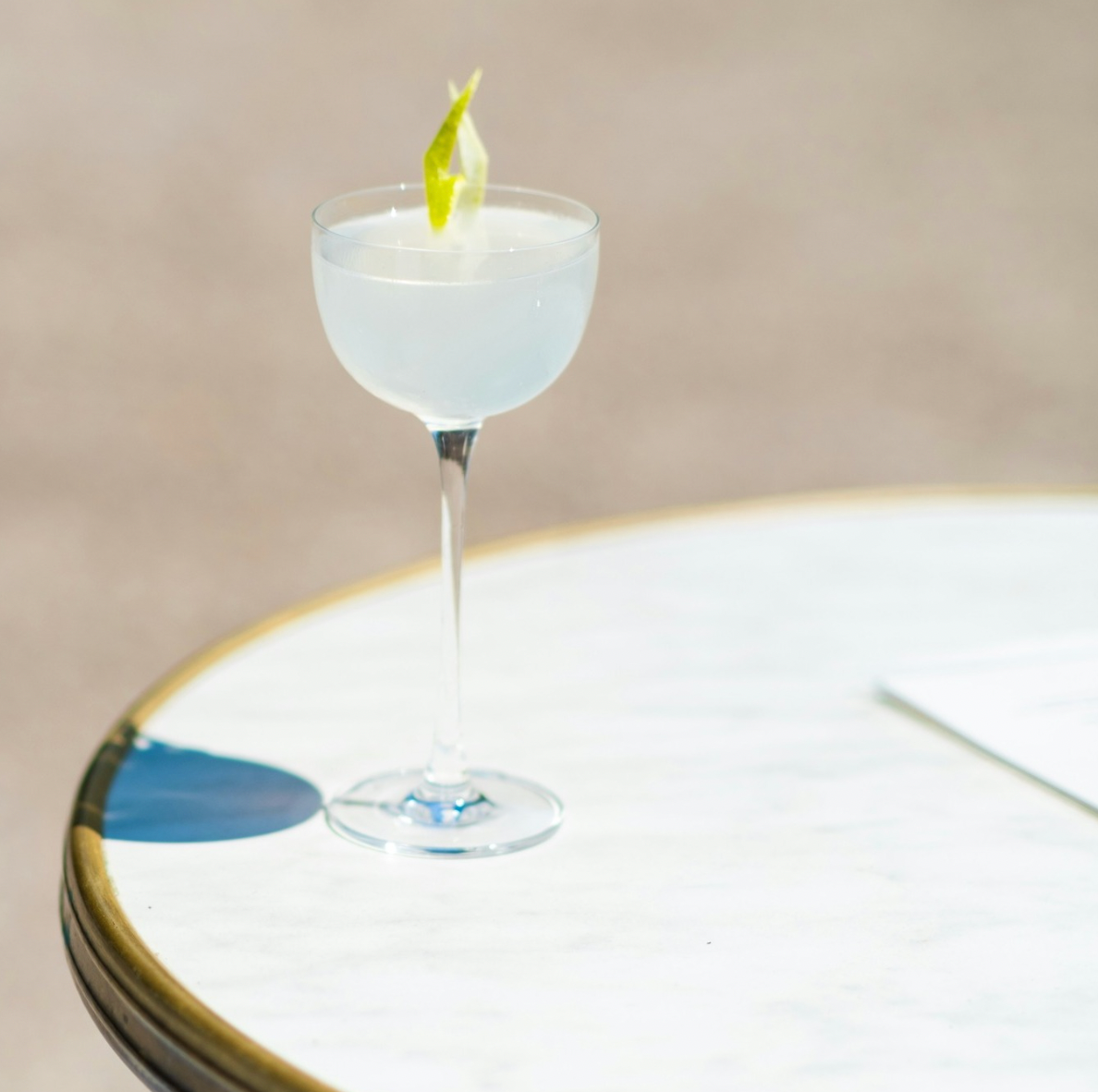 Cocktail in a glass with a lemon twist on a reflective surface