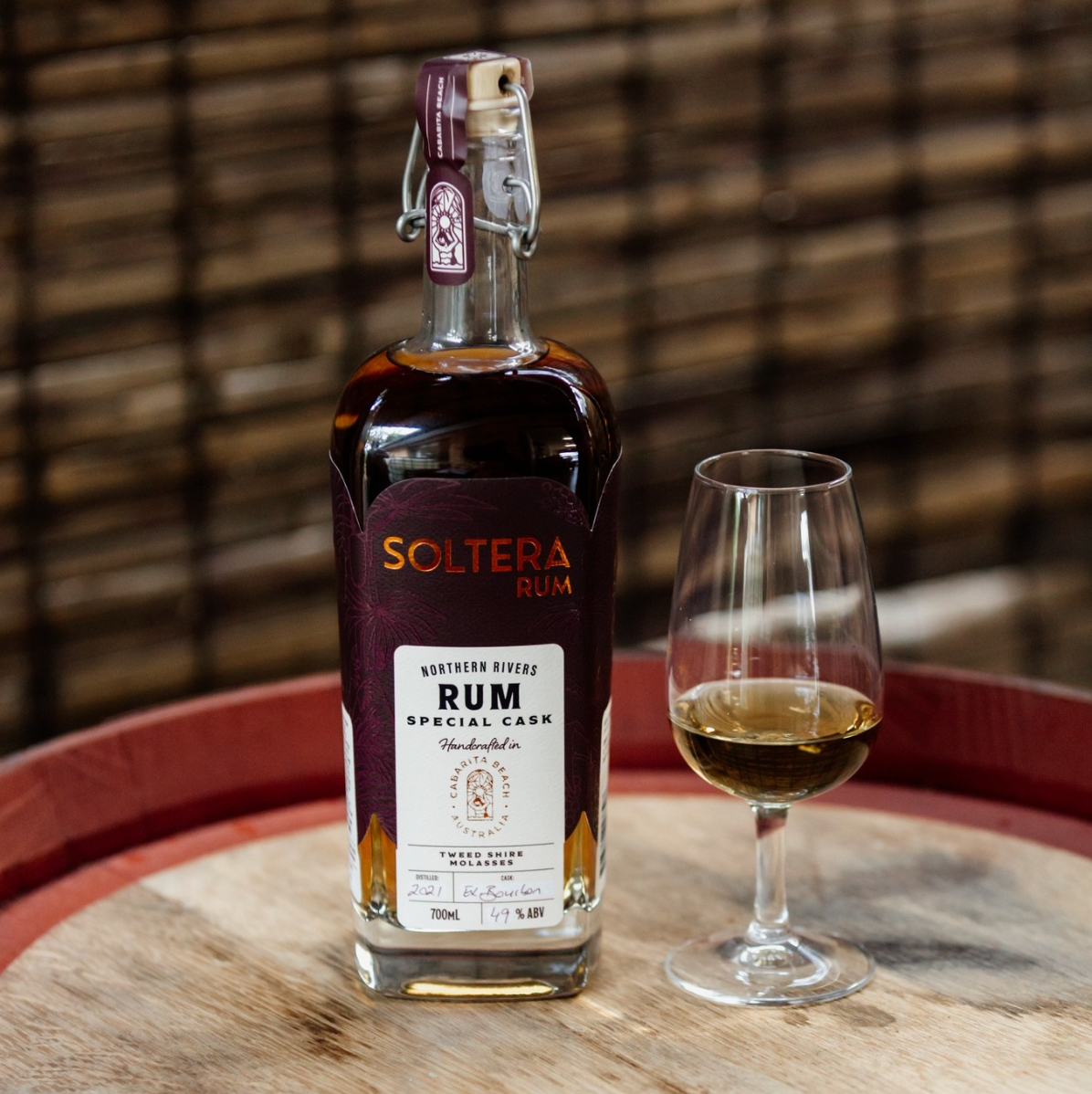 Soltera Rum bottle with a glass of rum on a wooden barrel